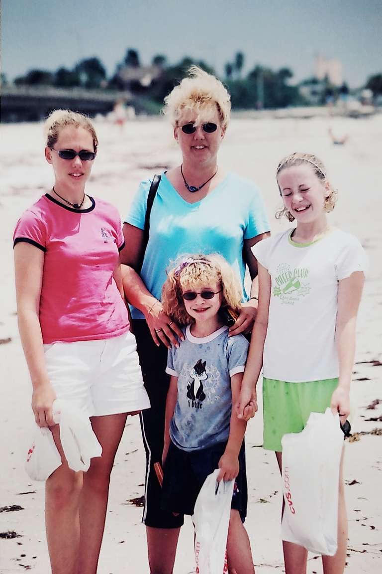 Beach photo of mom with three young daughters.