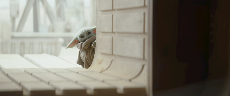 The Child (Baby Yoda) peers through a window. The Mandalorian, Season 2.