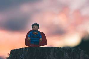 Long shot of Lego Super Man atop a stump.