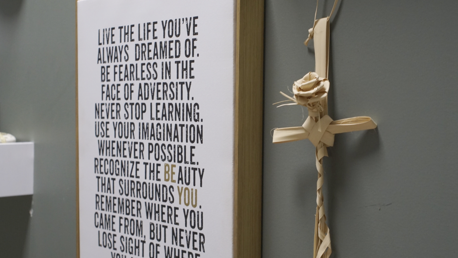 Close-up on inspirational sign and palmetto cross on Sensei Sheri's wall.