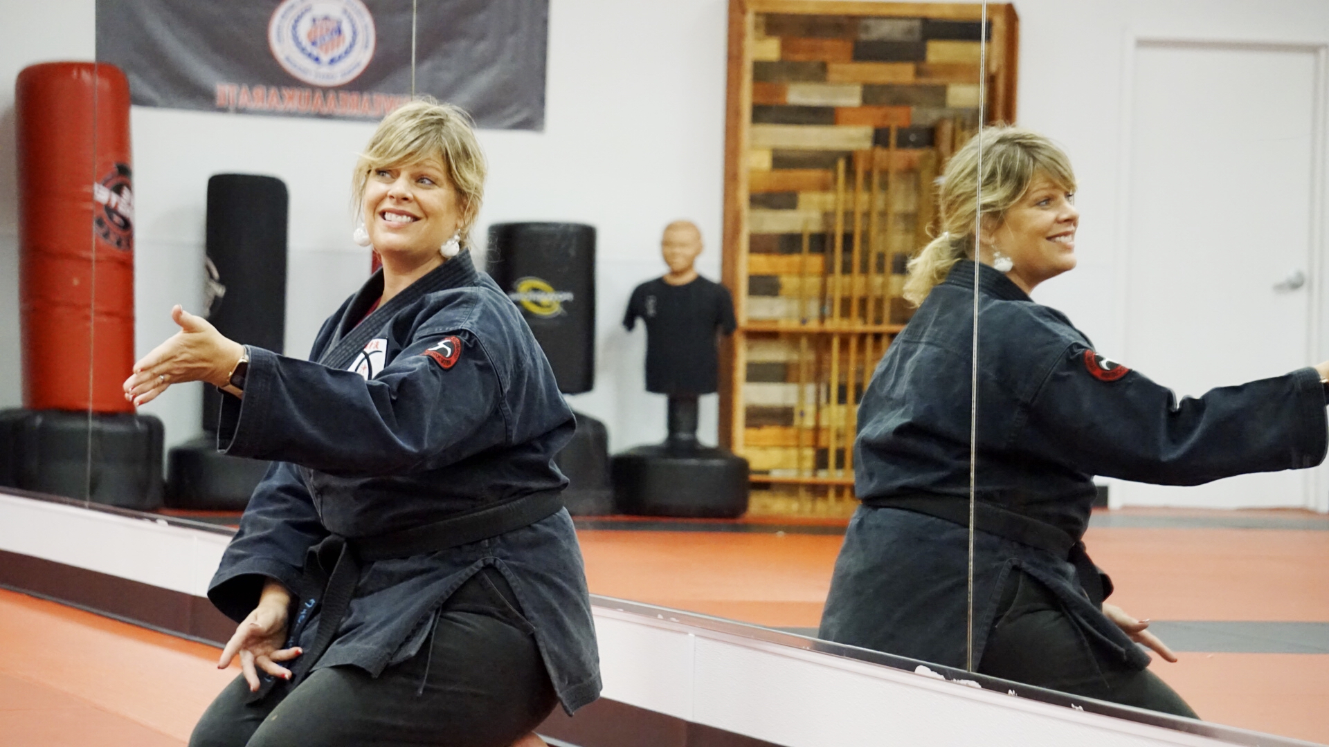 Sesnei Sheri kneels, smiles, and motions toward her students.