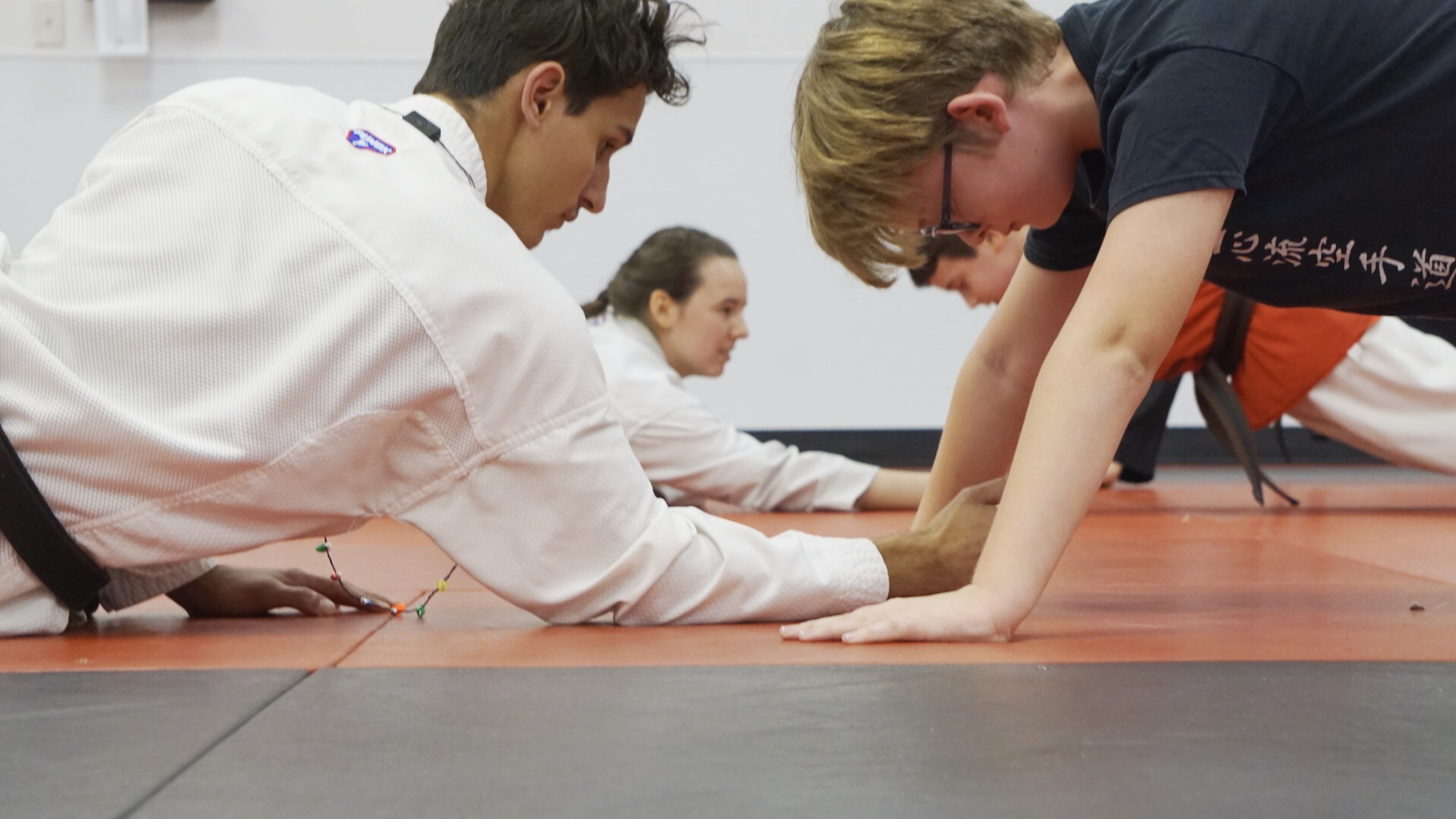 Teen sensei motivates a student during pushups.