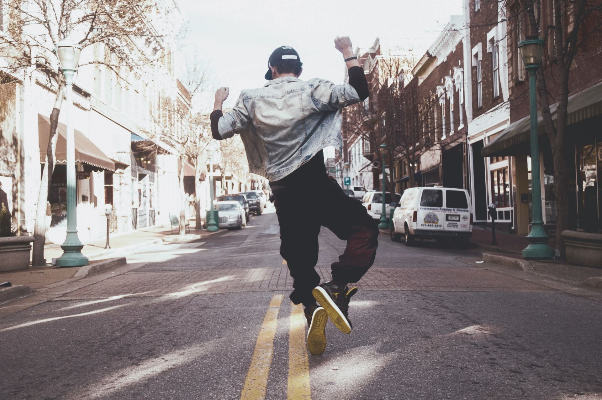 Man jumping for joy down a city street.
