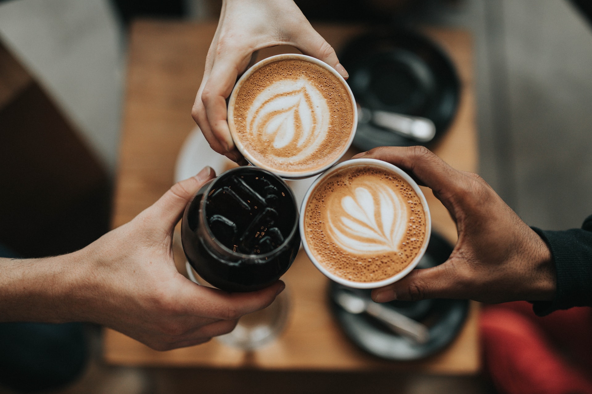 Cheers! Overhead shot of three coffees: cold brew and two lattes.